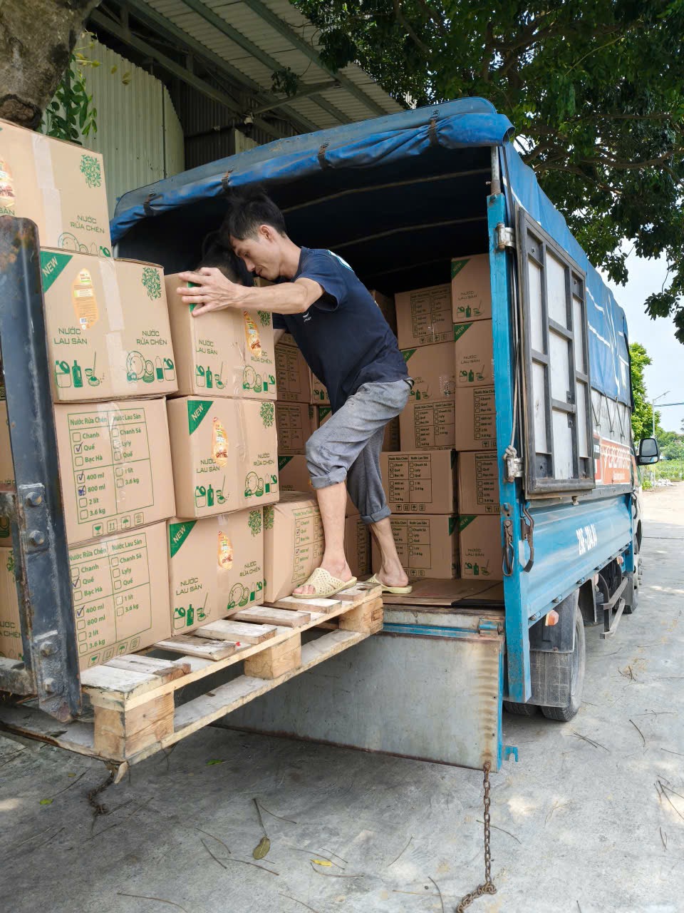 Công nhân xếp thùng hàng nước giặt vào xe giao đi tỉnh